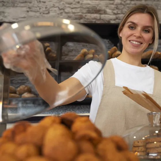 Marta solleva la campana di vetro sui dolci del banco